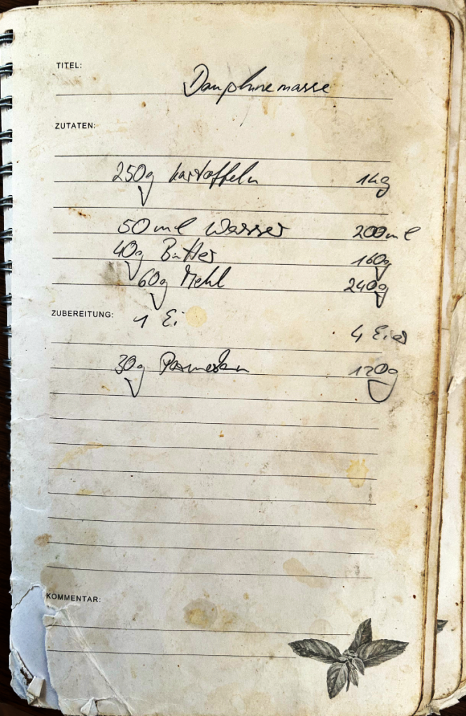 Handgeschriebenes Rezept für Dauphinemasse in altem Notizbuch mit Zutaten auf Deutsch