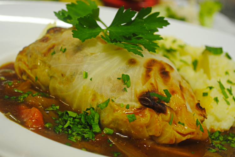 Spitzkohlroulade mit Kartoffelpüree und brauner Sauce auf weißem Teller, garniert mit Petersilie