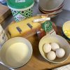 Zutaten für Käsebiskuit: Le Gruyère, Eier, Piment d'Espelette, Maldon Salz und Mehl auf Holzbrett