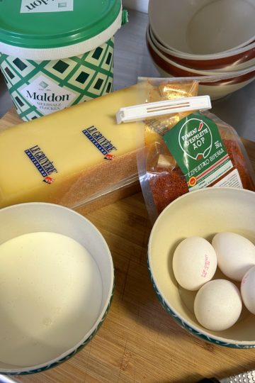 Zutaten für Käsebiskuit: Le Gruyère, Eier, Piment d'Espelette, Maldon Salz und Mehl auf Holzbrett
