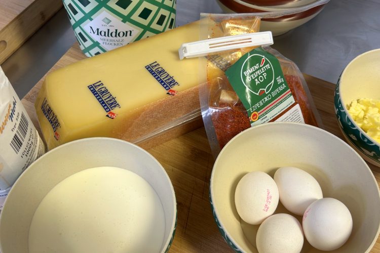 Zutaten für Käsebiskuit: Le Gruyère, Eier, Piment d'Espelette, Maldon Salz und Mehl auf Holzbrett